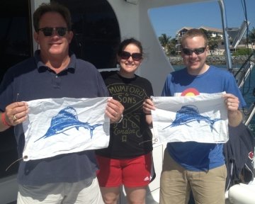 people on a boat holding blue marlin flags